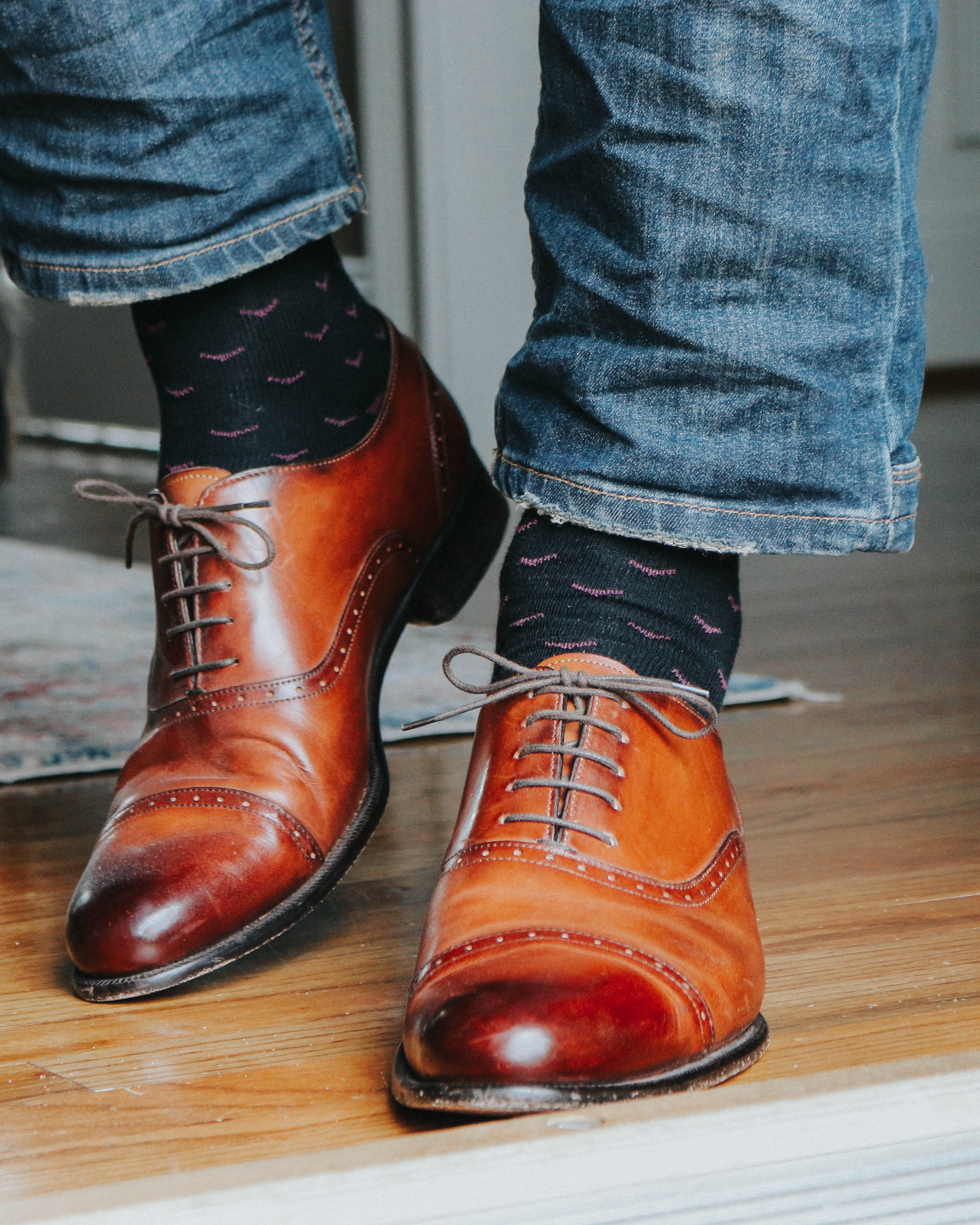 black over the calf dress socks with pink print, brown dress shoes, blue jeans