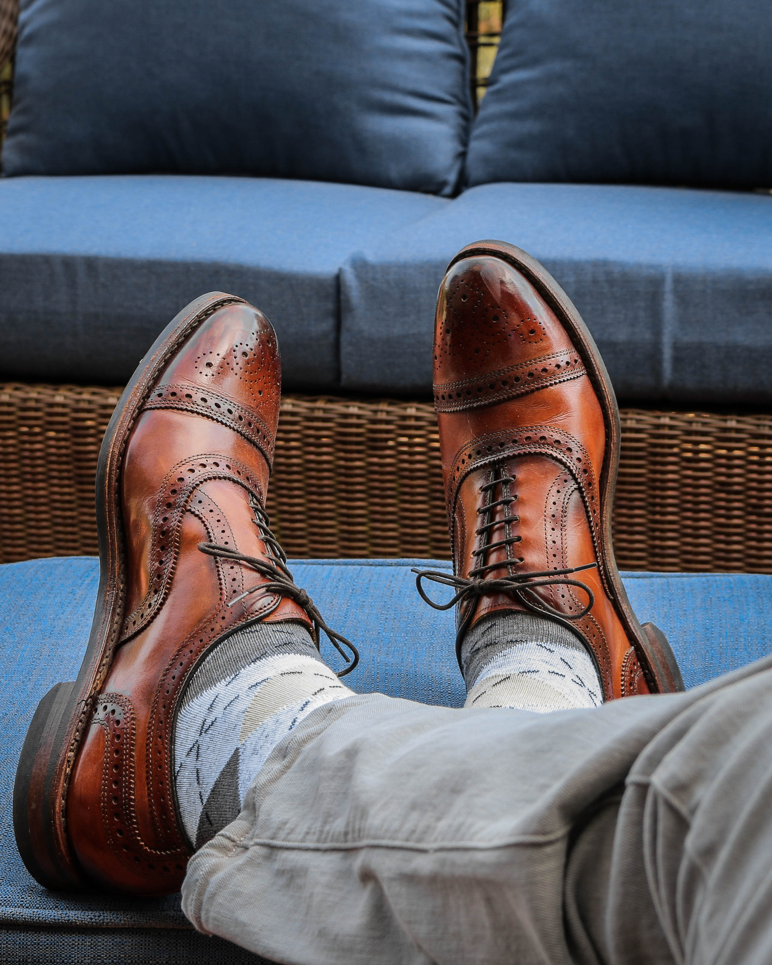 grey argyle print over the calf dress socks, brown dress shoes, grey pants, blue couches