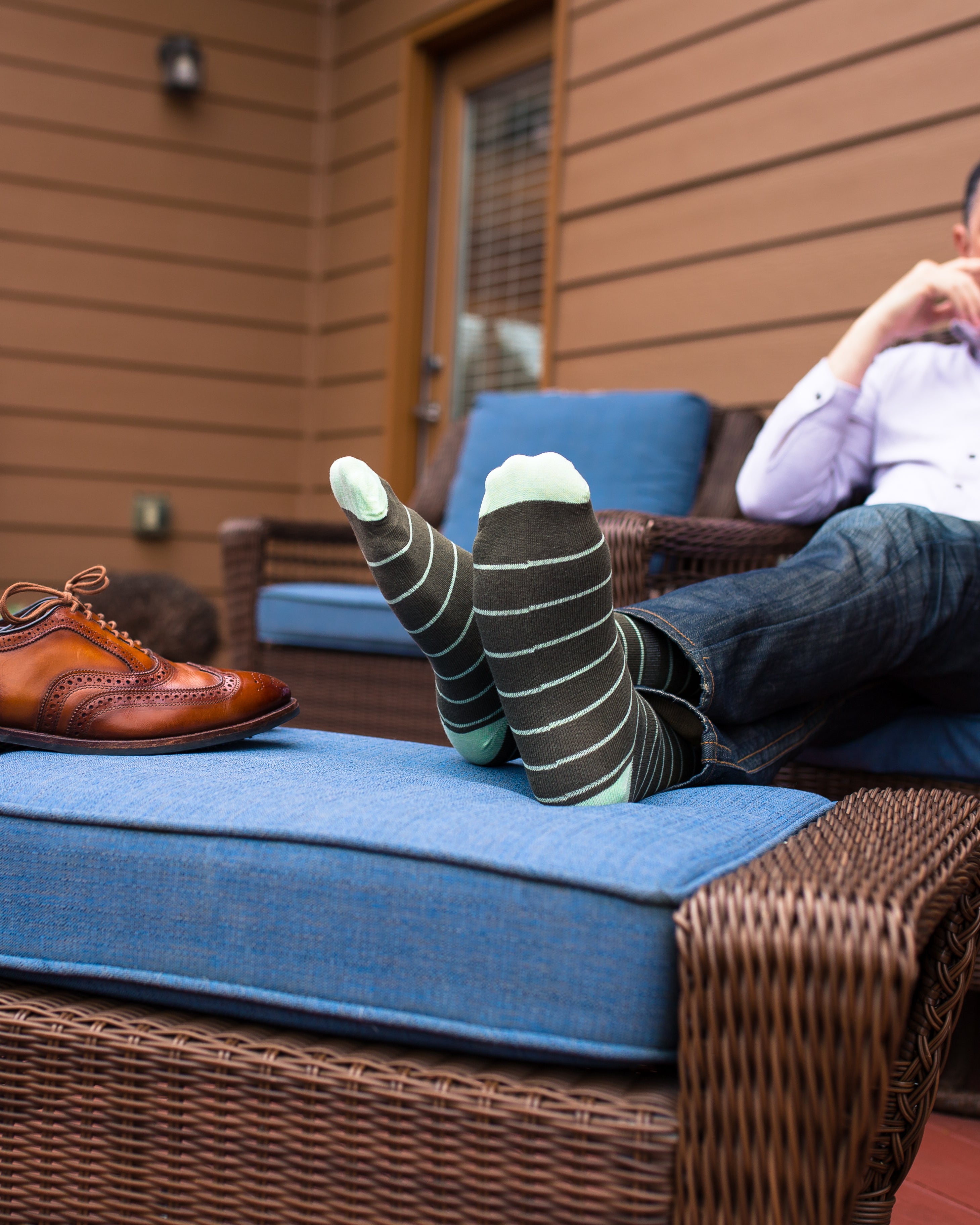dark grey over the calf dress socks with aqua blue stripes, blue jeans, on a chair