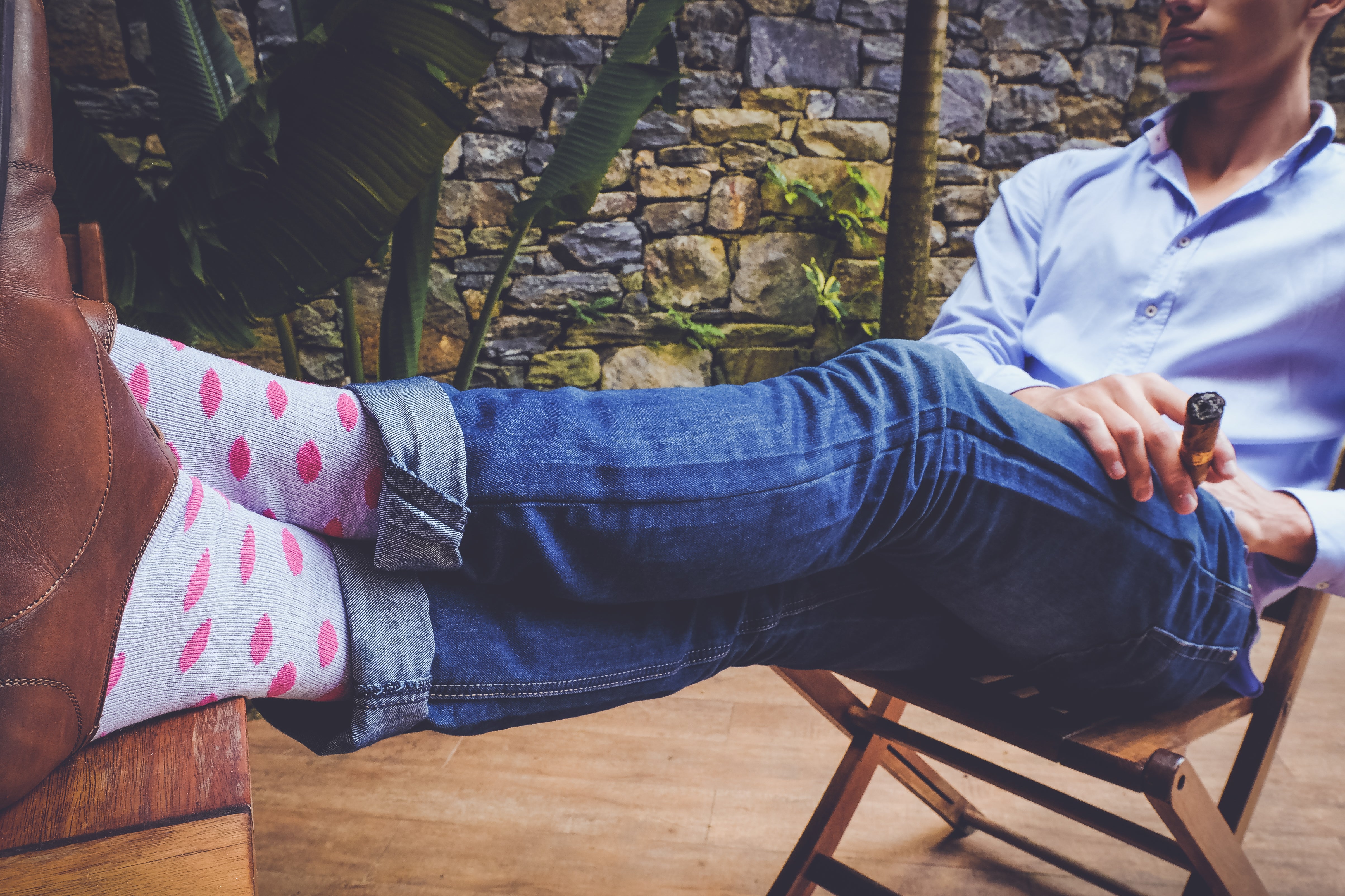 light blue over the calf dress socks with pink oval pattern, brown dress shoes, blue jeans, cigar in hand, light blue dress shirt