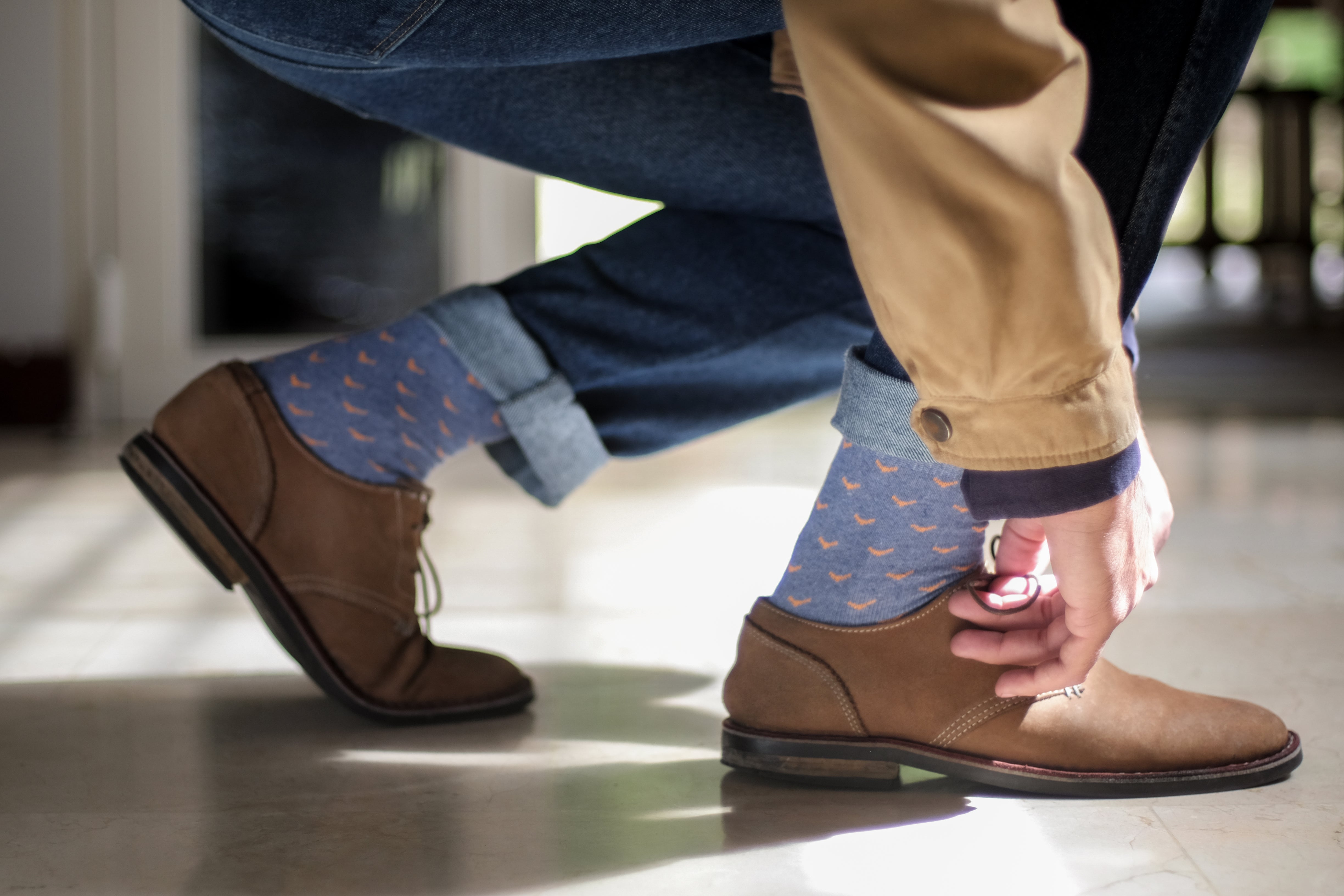 light blue over the calf dress socks with orange birds, light brown dress shoes, and blue jeans
