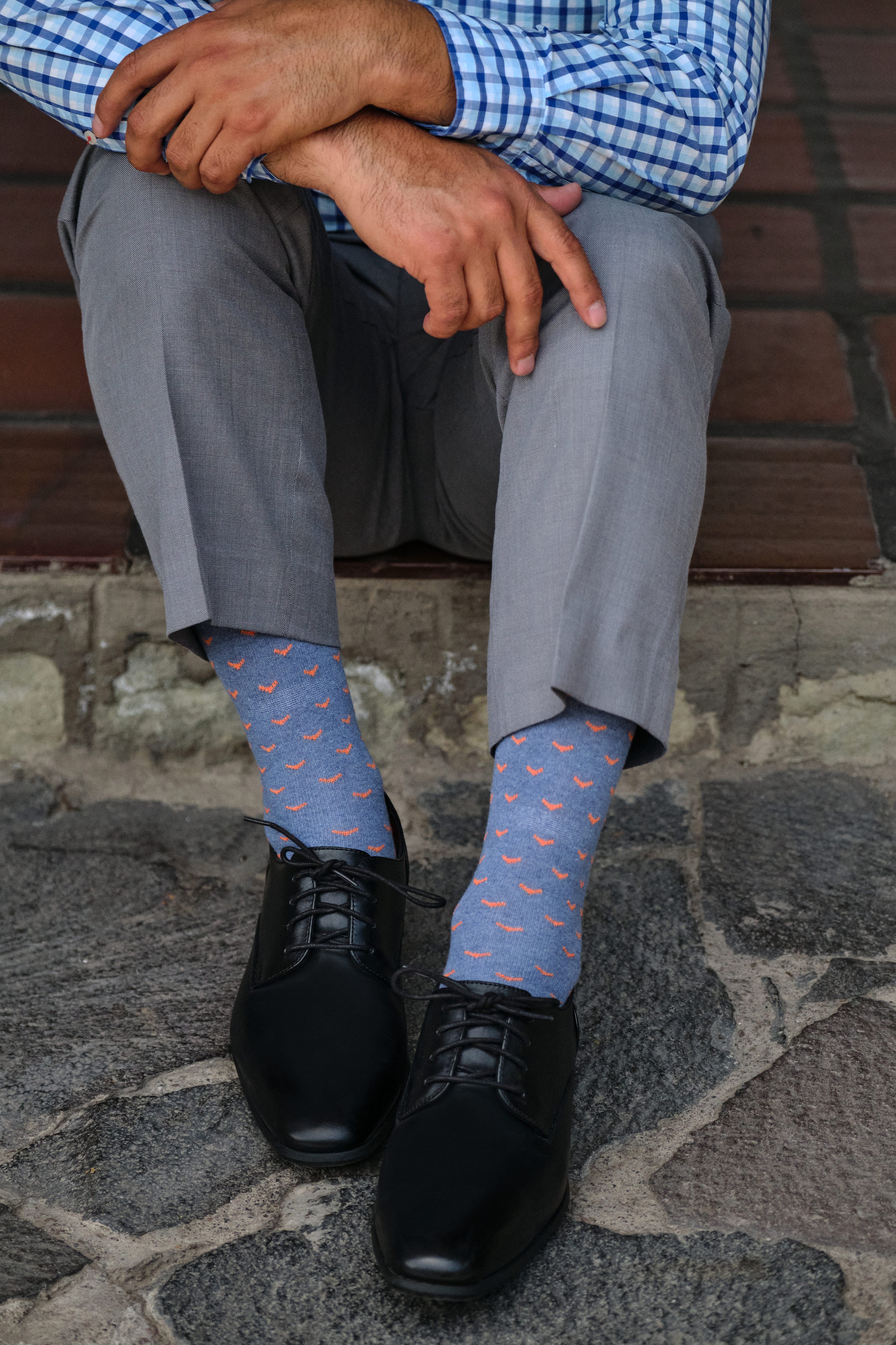 light blue mid calf dress socks with orange bird prints, black dress shoes, grey dress pants, plaid dress shirt