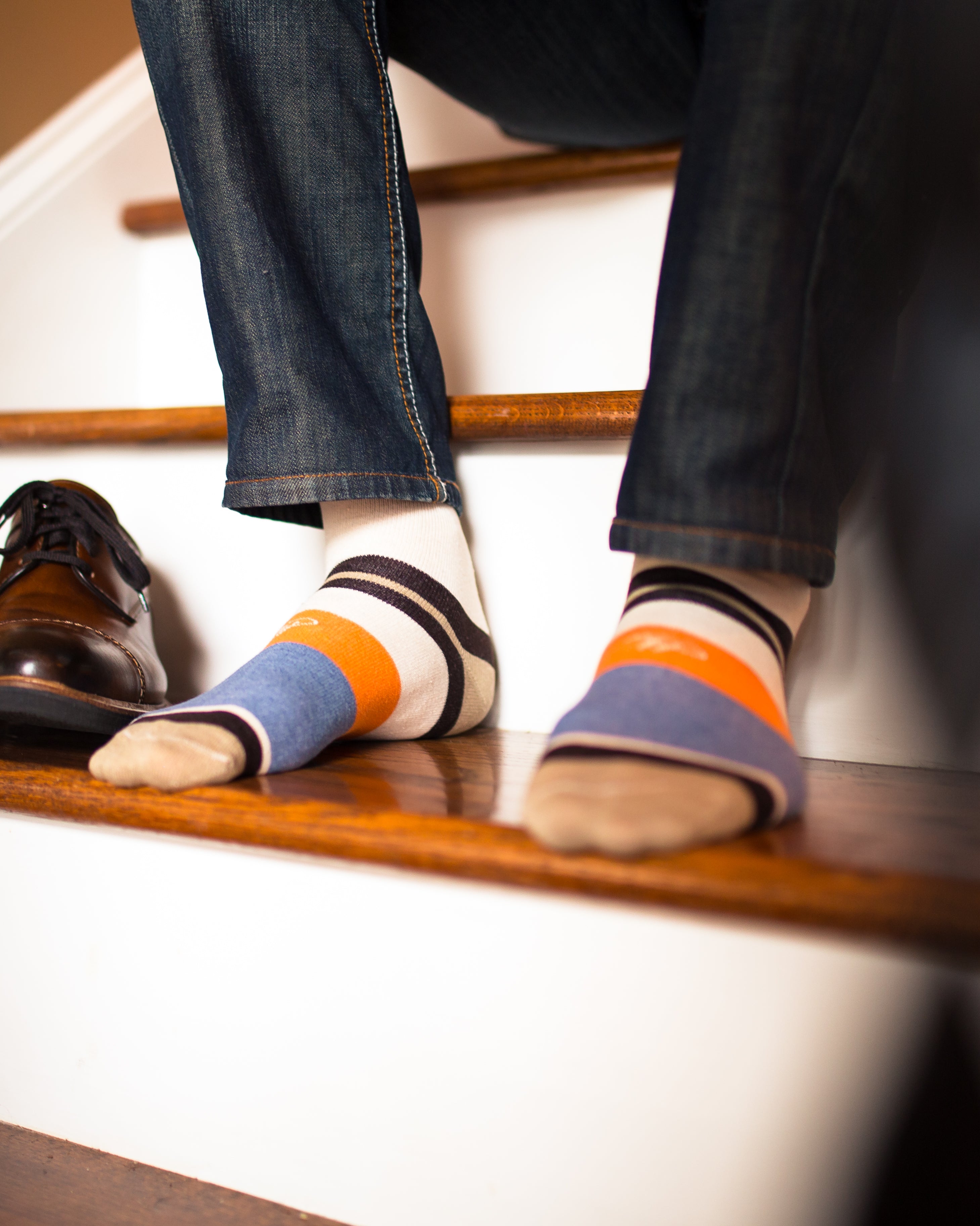beige over the calf dress socks with orange and light blue stripes, blue jeans, brown dress shoe