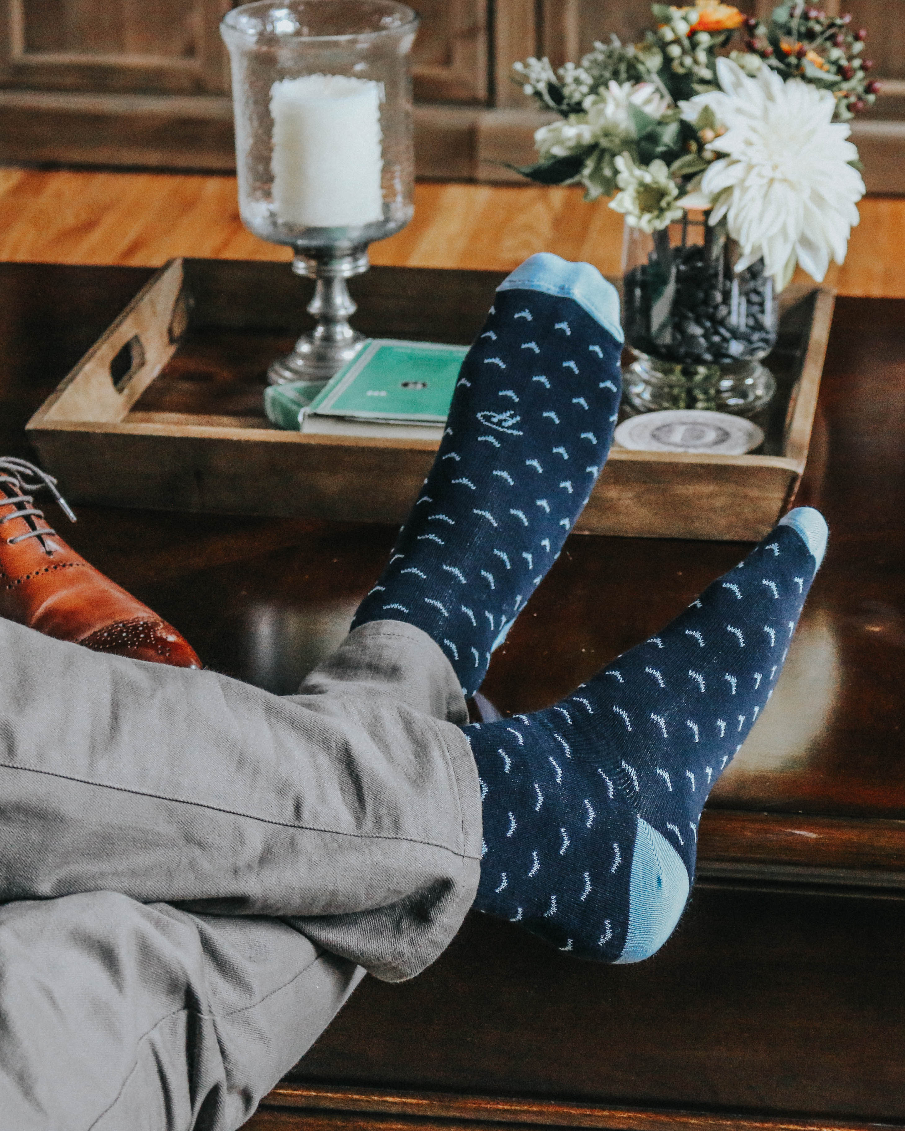 blue over the calf dress socks with light blue print, casual grey pants, on a table