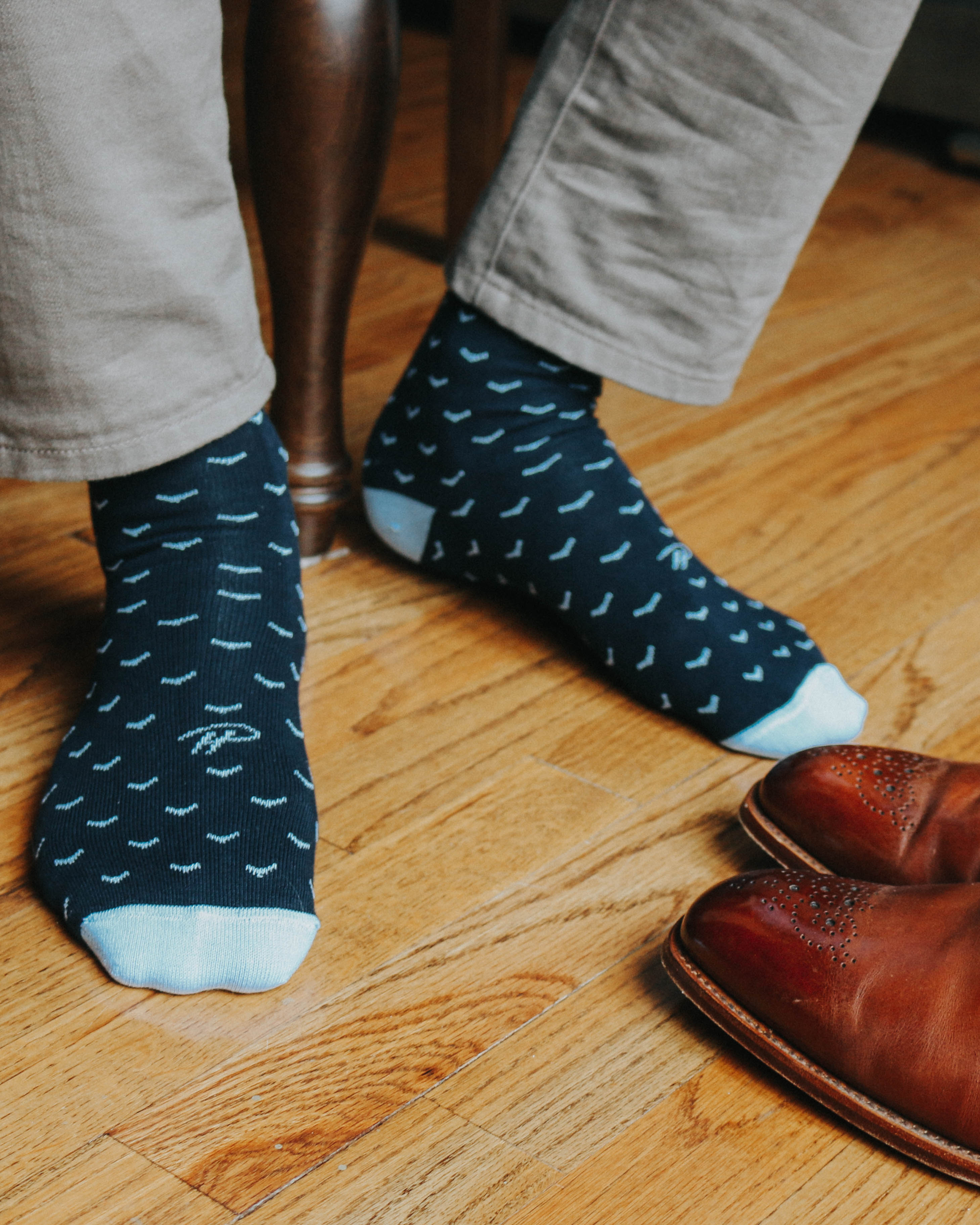 blue over the calf dress socks with light blue print, brown dress shoes, grey casual pants