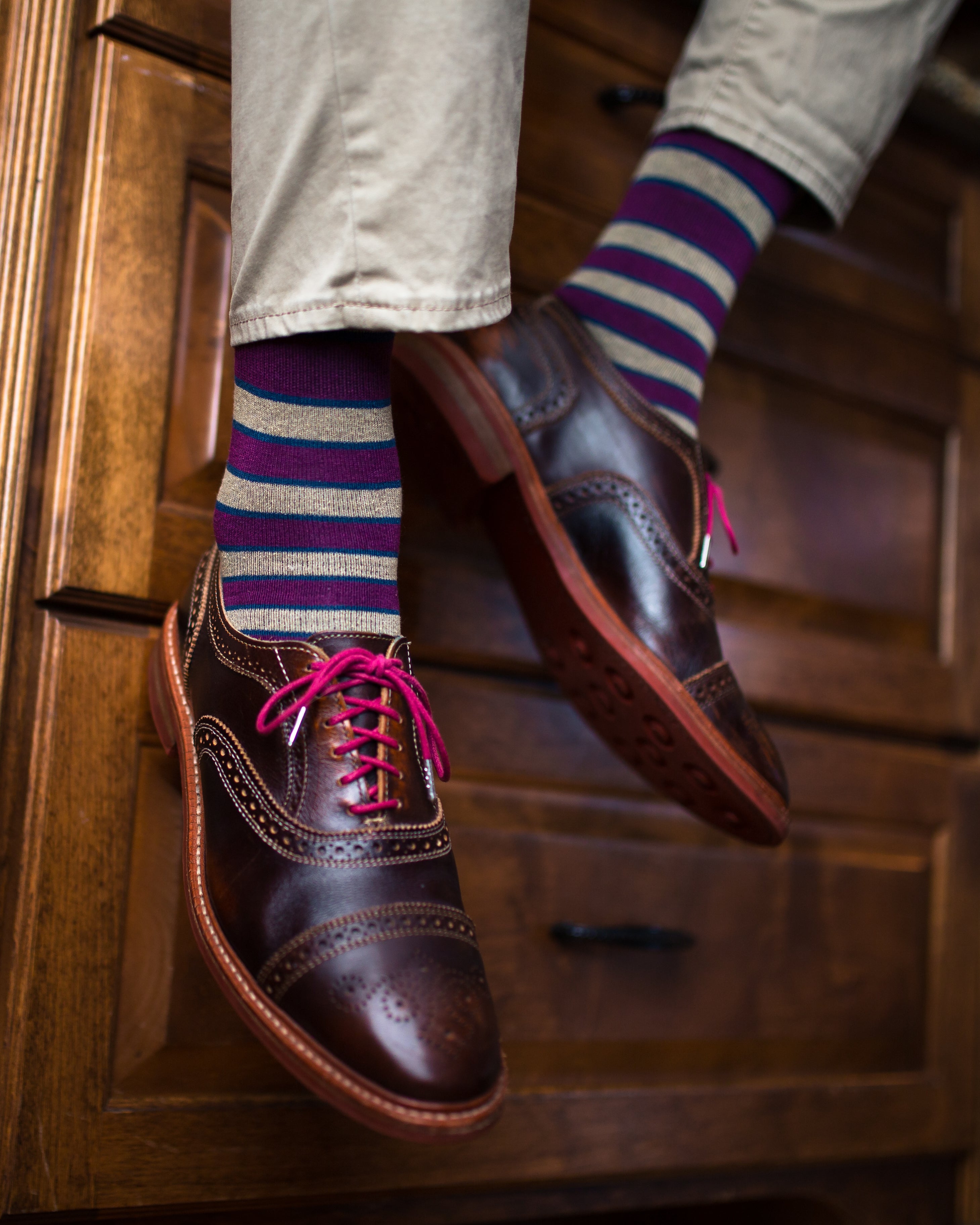 burgundy and light brown striped over the calf dress socks, dark brown dress shoes with pink laces, light beige pants