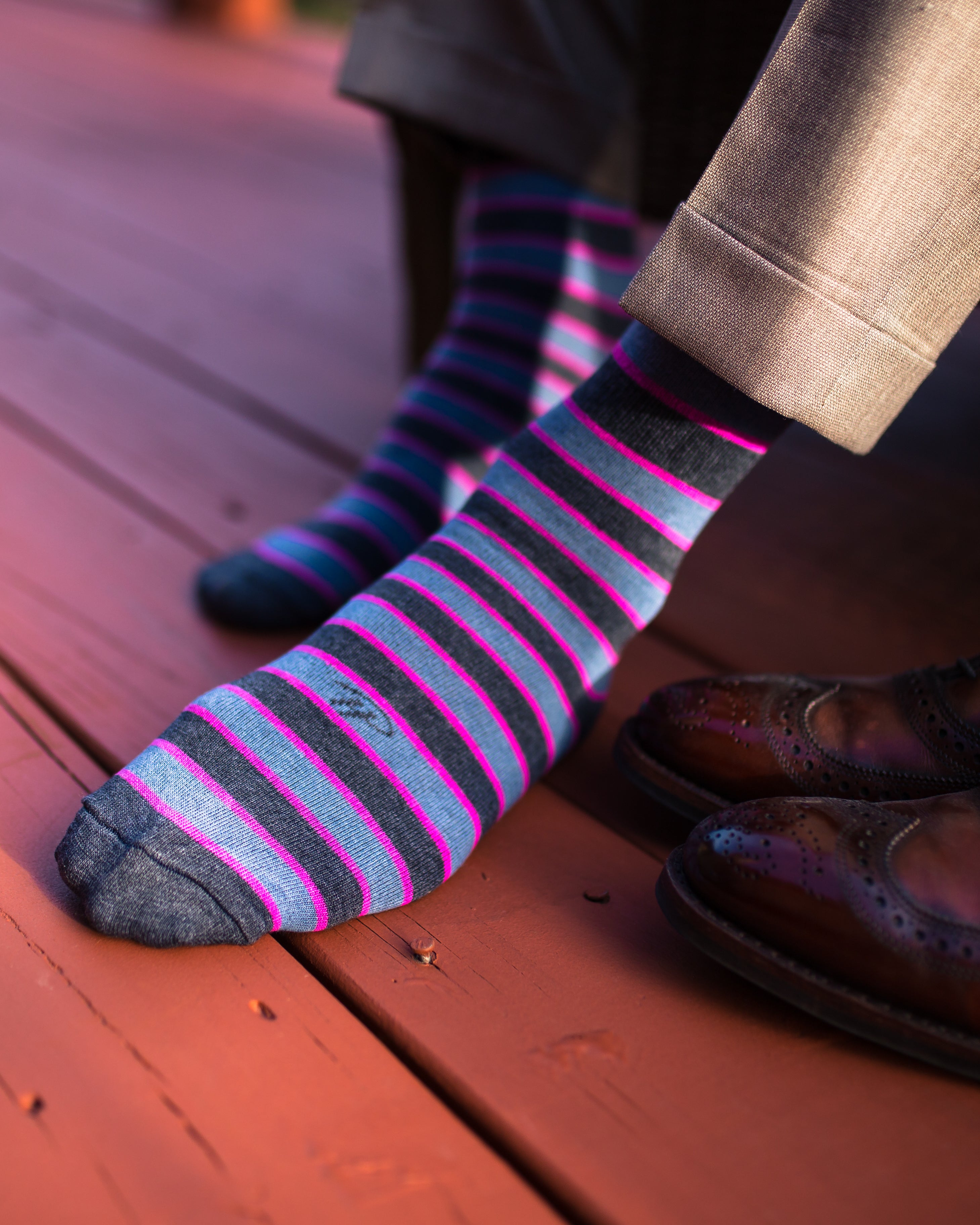dark grey light blue and pink striped over the calf dress socks, light brown pants, brown dress shoes on floor