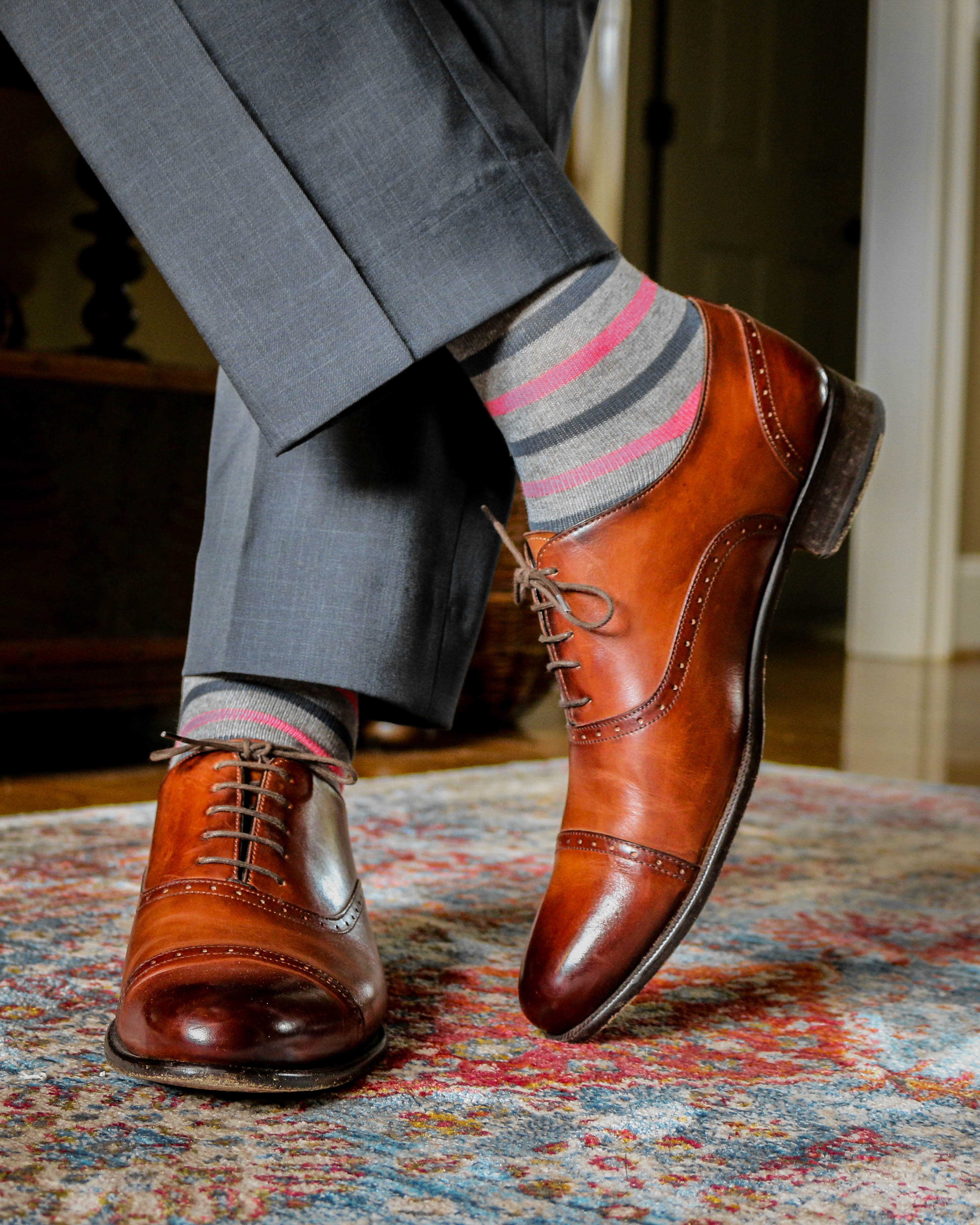 light grey over the calf dress socks with pink and grey stripes, brown dress shoes, grey dress pants, on a carpet