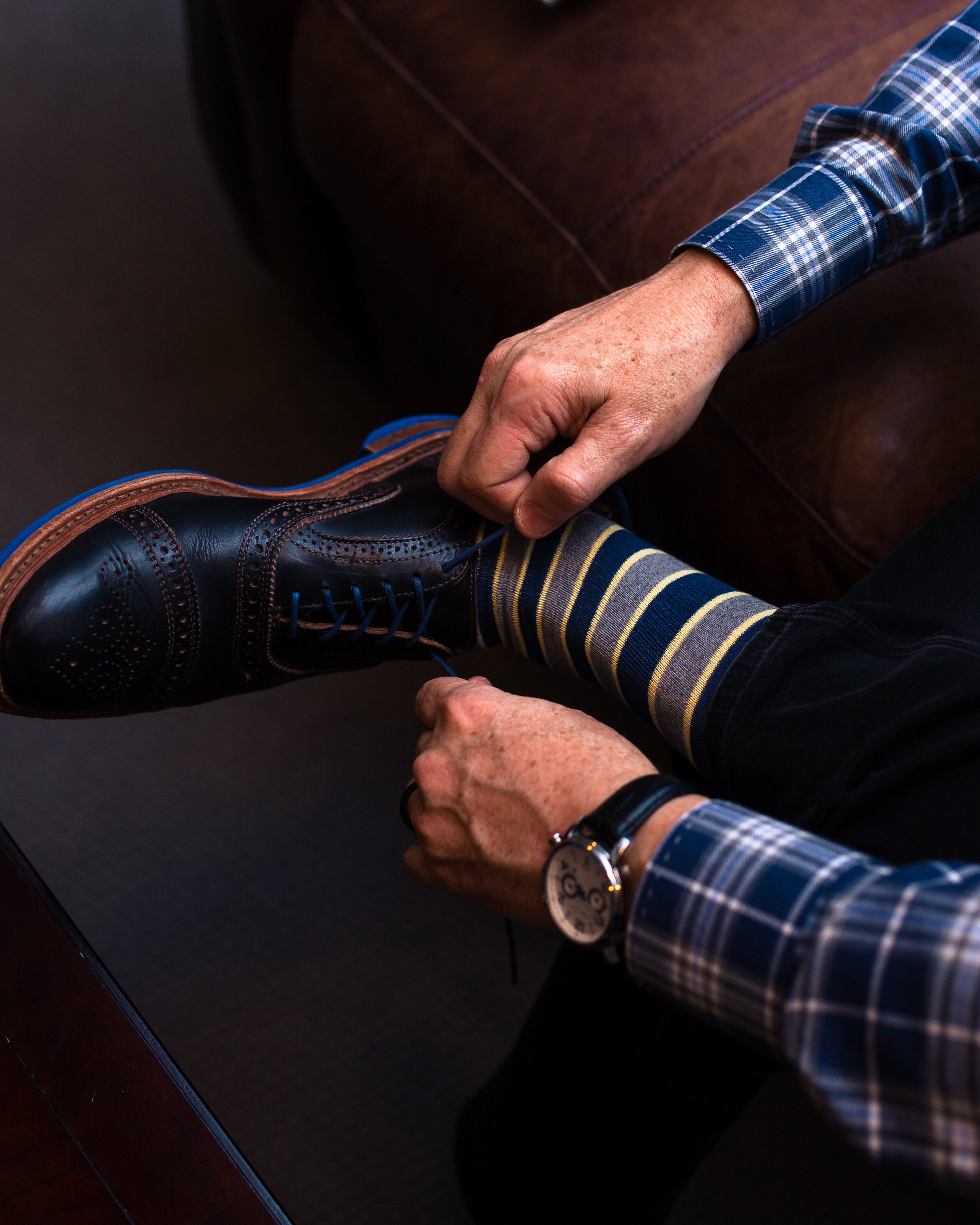 navy blue yellow and grey striped over the calf dress socks, black dress shoes with blue laces, black watch, black jeans