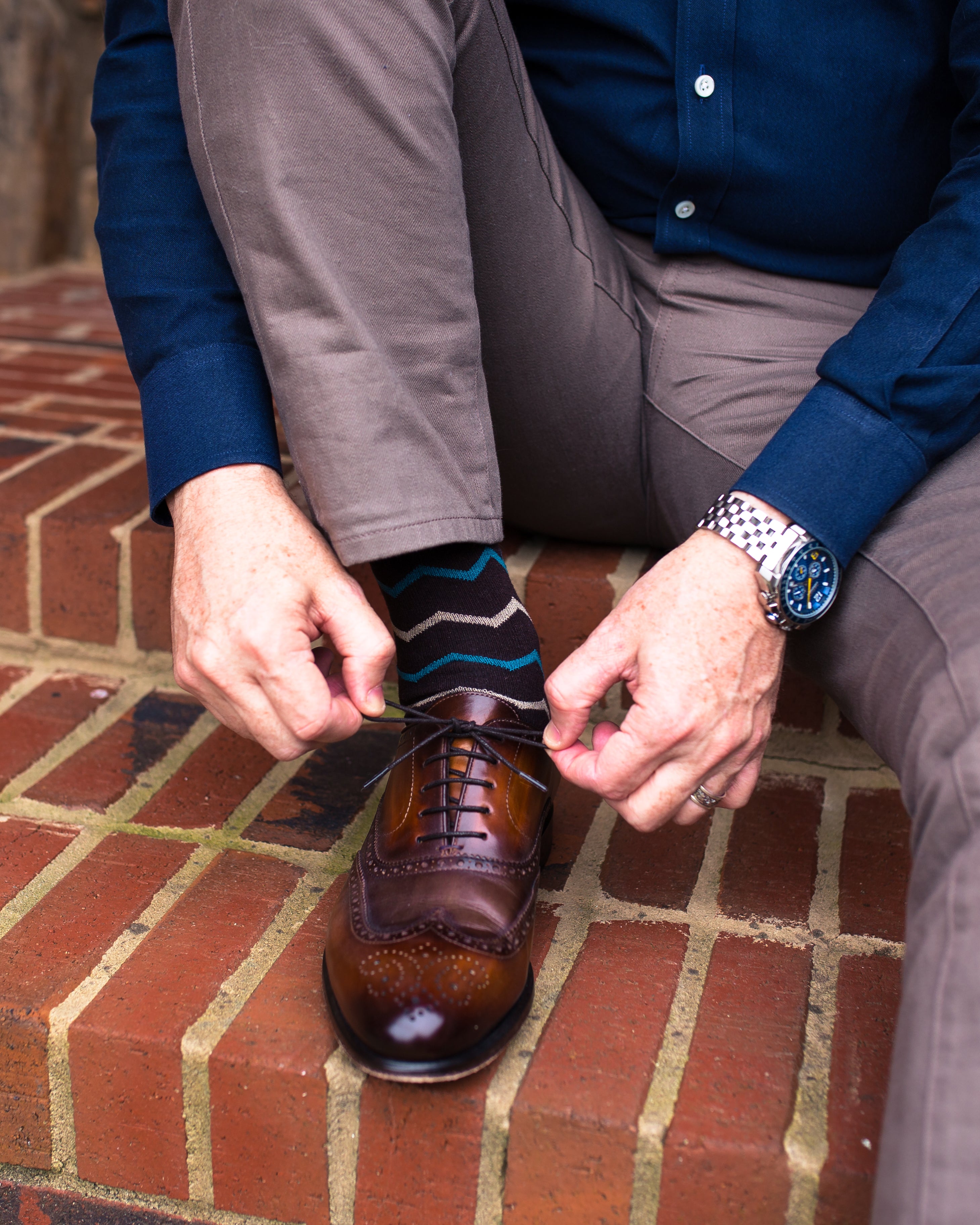 purple over the calf dress socks with blue and yellows zigzag lines, brown shoes, grey pants, and a watch