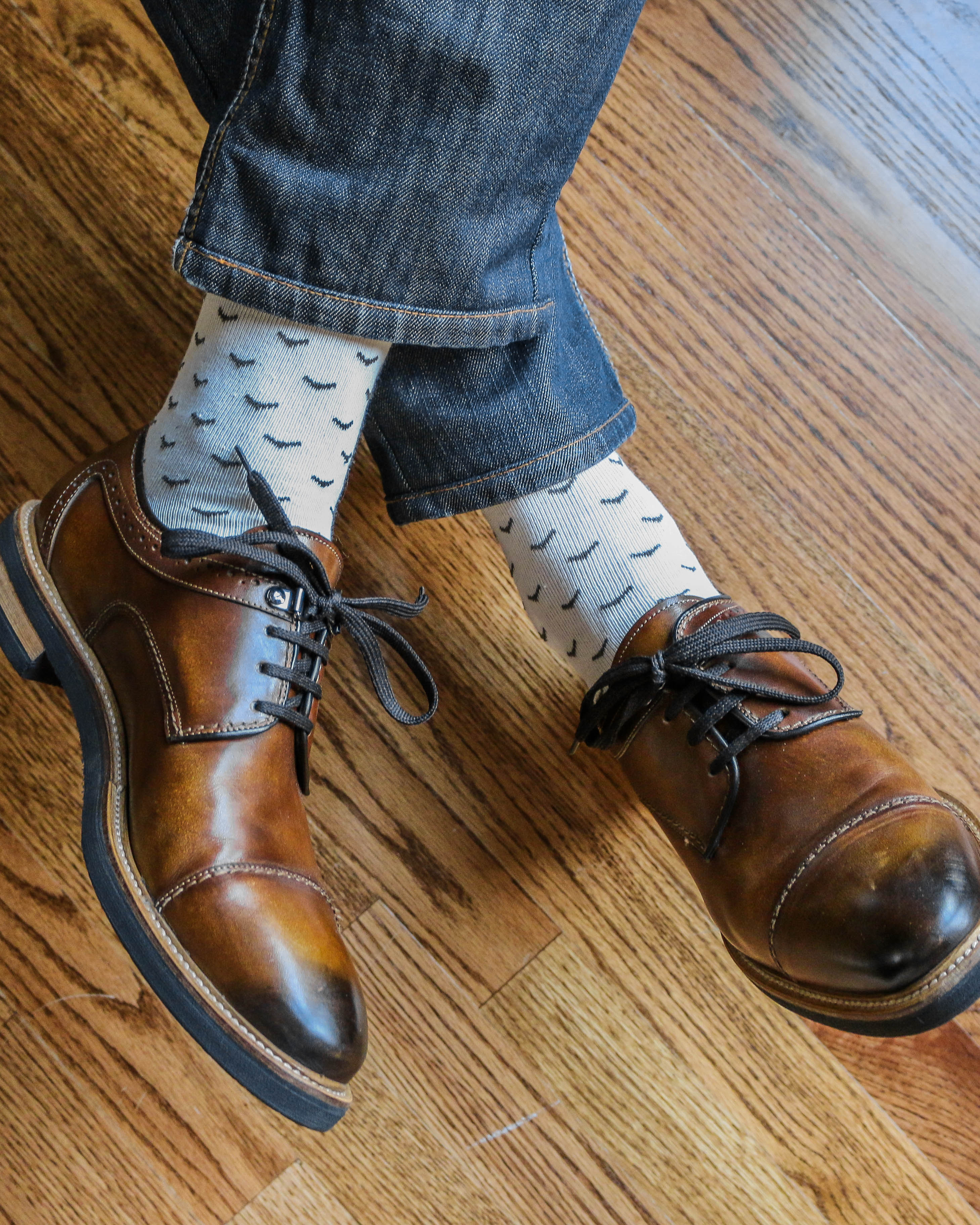 white over the calf dress socks with black prints, brown dress shoes, blue jeans