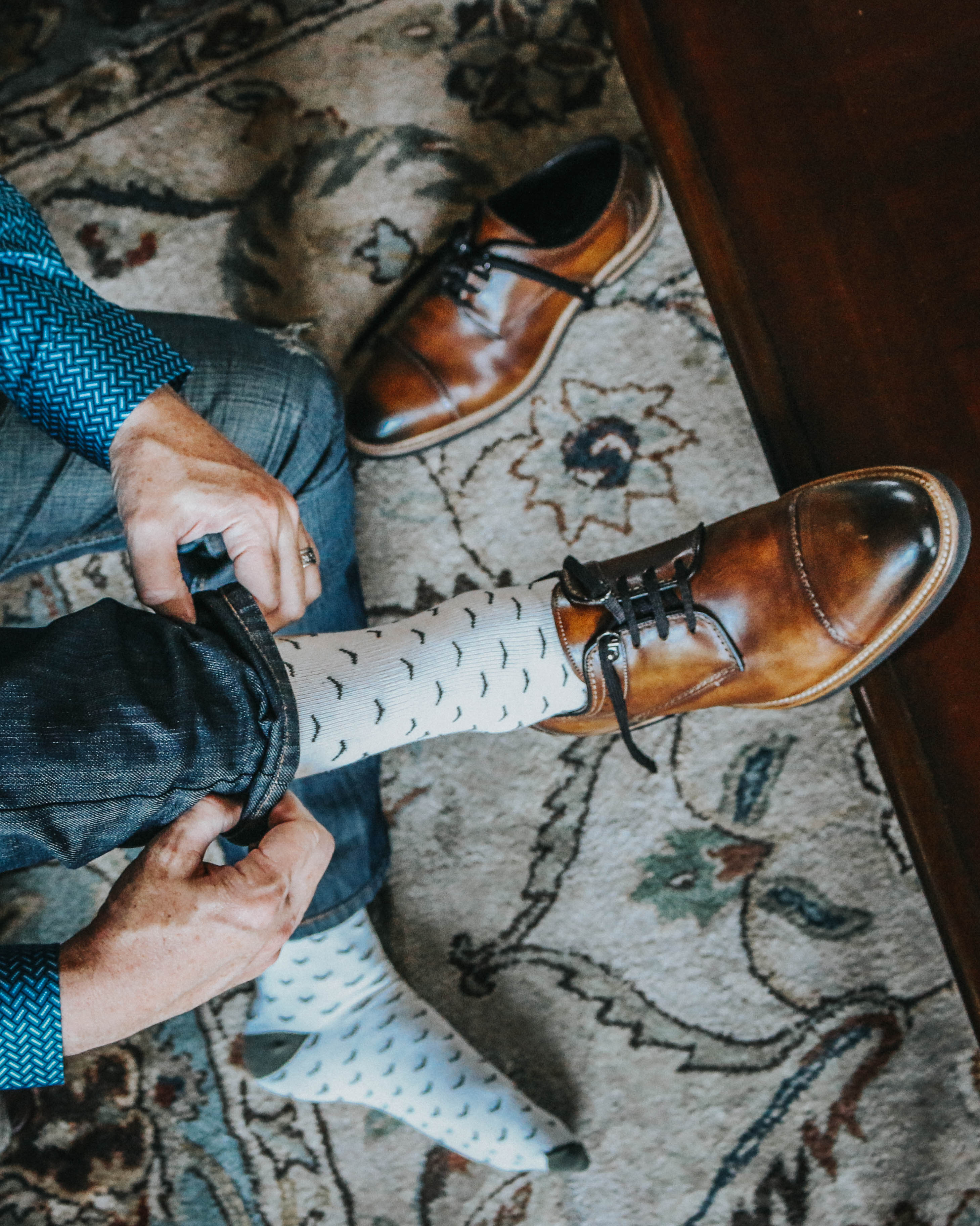 white over the calf dress socks with black print, brown dress shoes with black laces, blue jeans