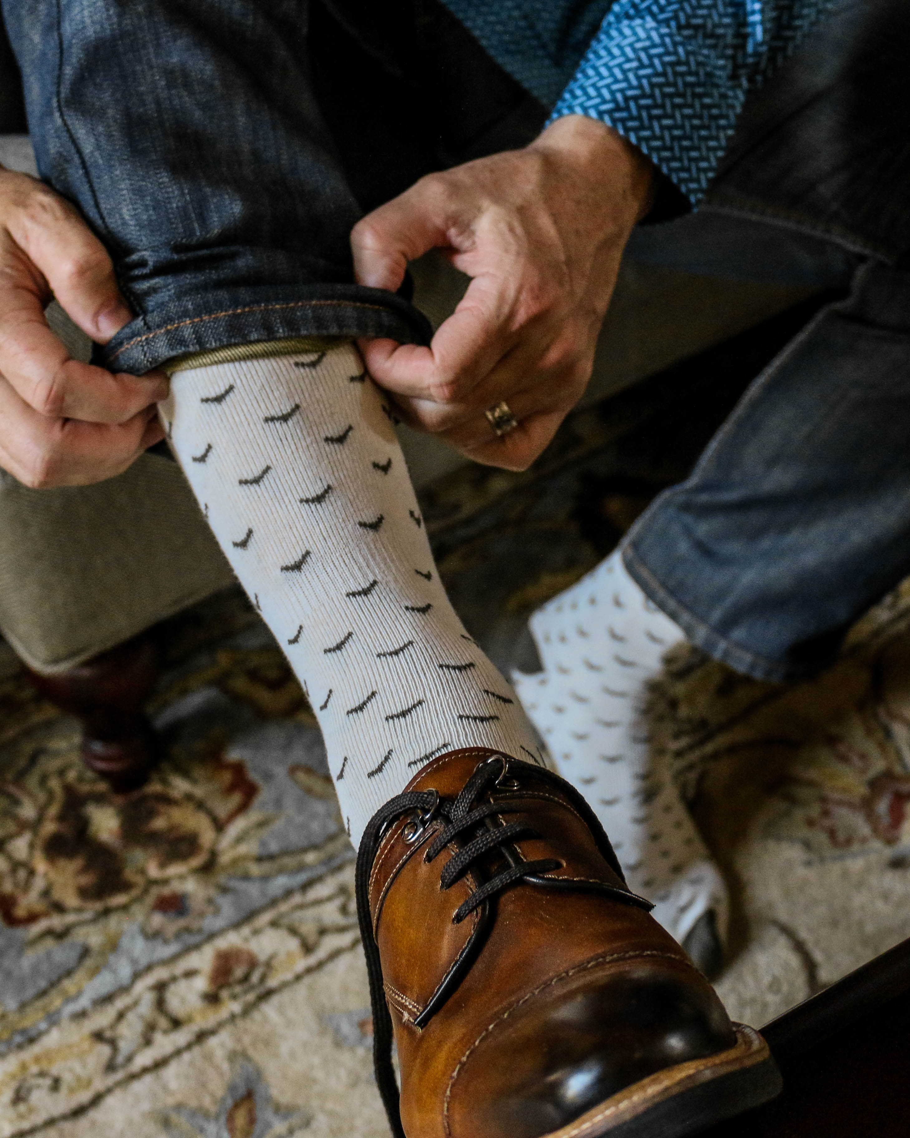 white over the calf dress socks with black print, brown dress shoes with black laces, blue jeans, blue dress shirt
