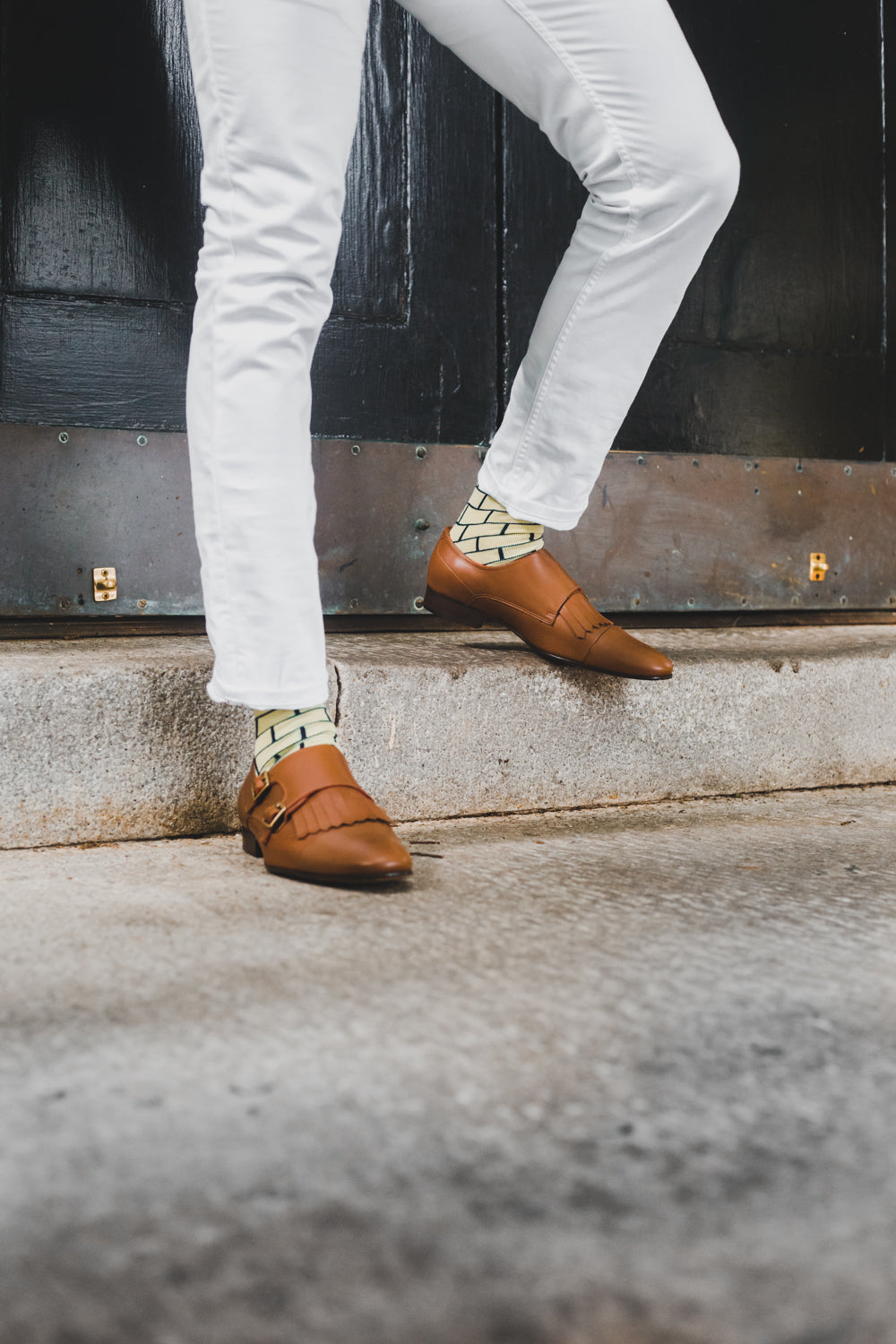 yellow over the calf dress socks with black brick line pattern, brown dress shoes, white pants, on a step