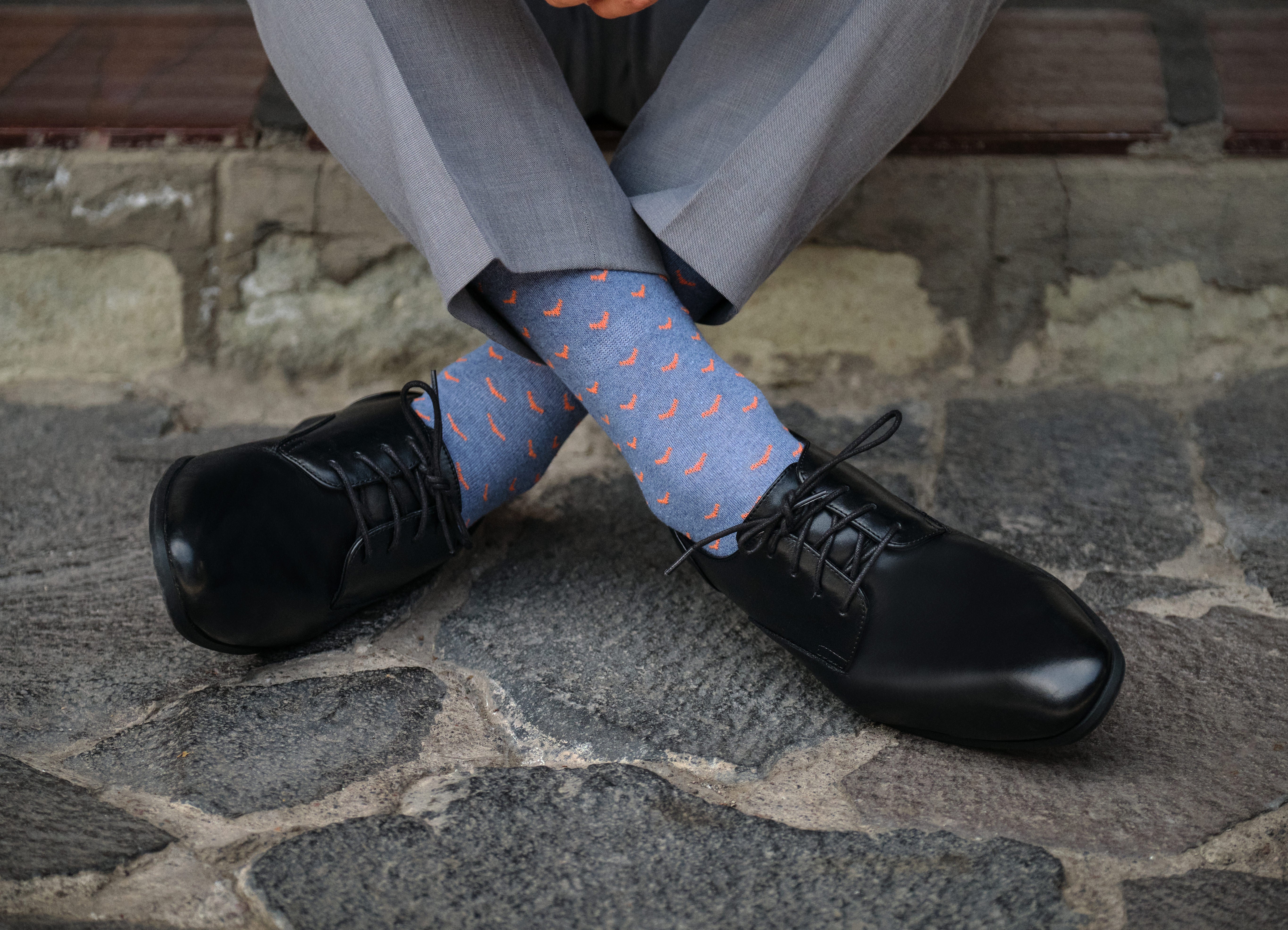 light blue mid calf dress socks with orange bird prints, black dress shoes, grey dress pants