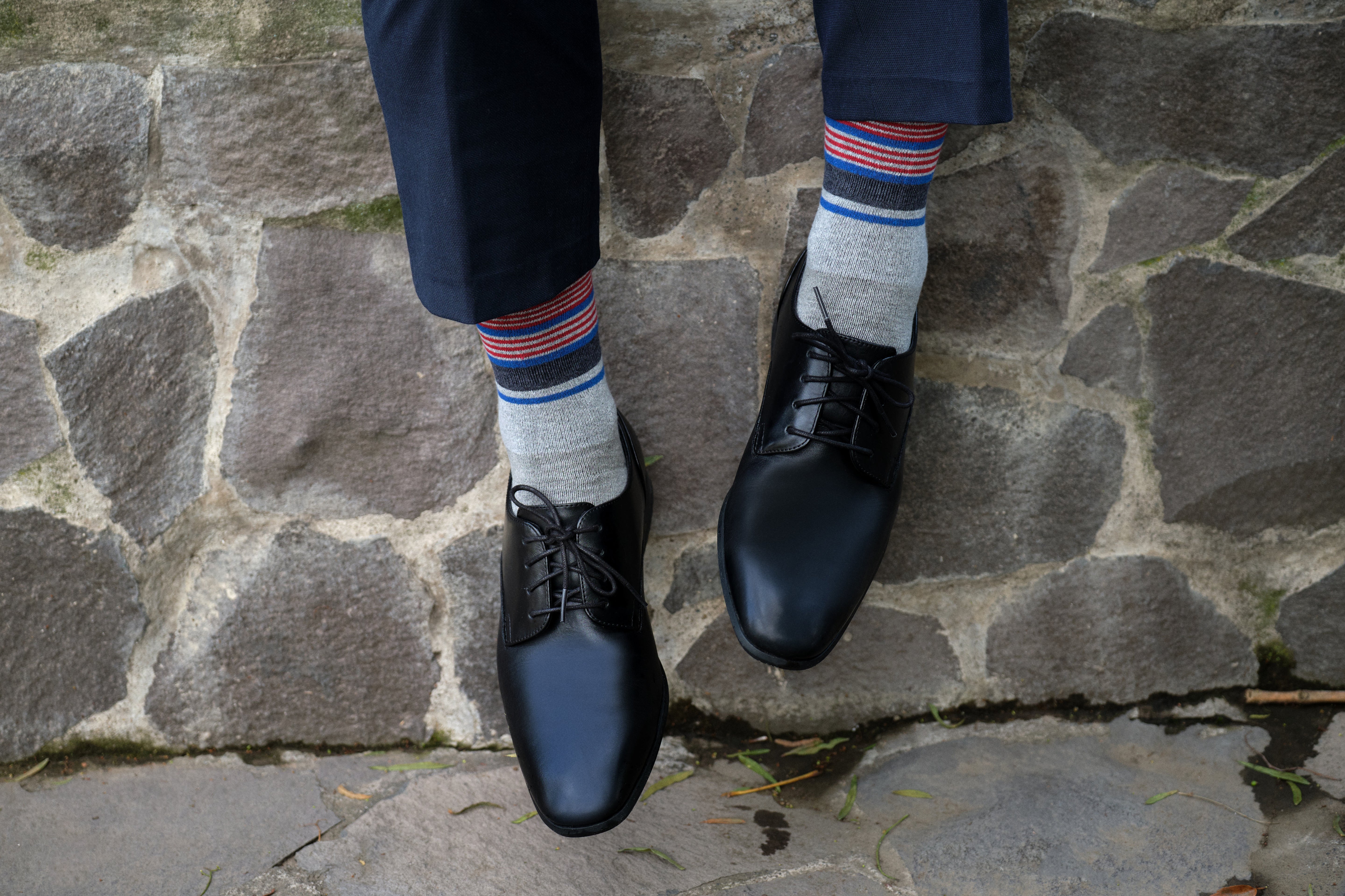 light grey mid calf dress socks with black blue and red stripes, black dress shoes, navy dress pants