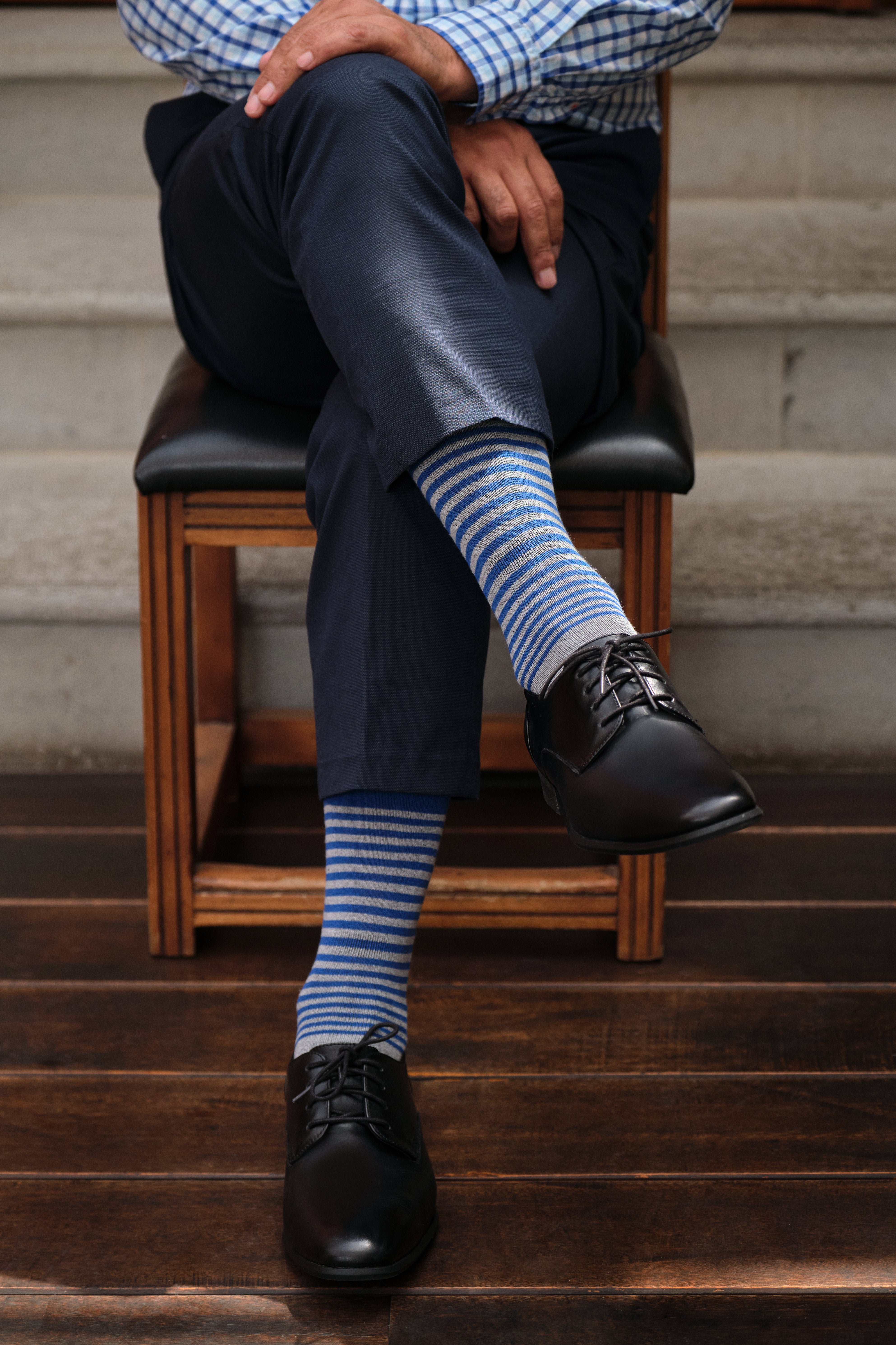 light grey mid calf dress socks with blue stripes, navy dress pants, black dress shoes, plaid button down shirt
