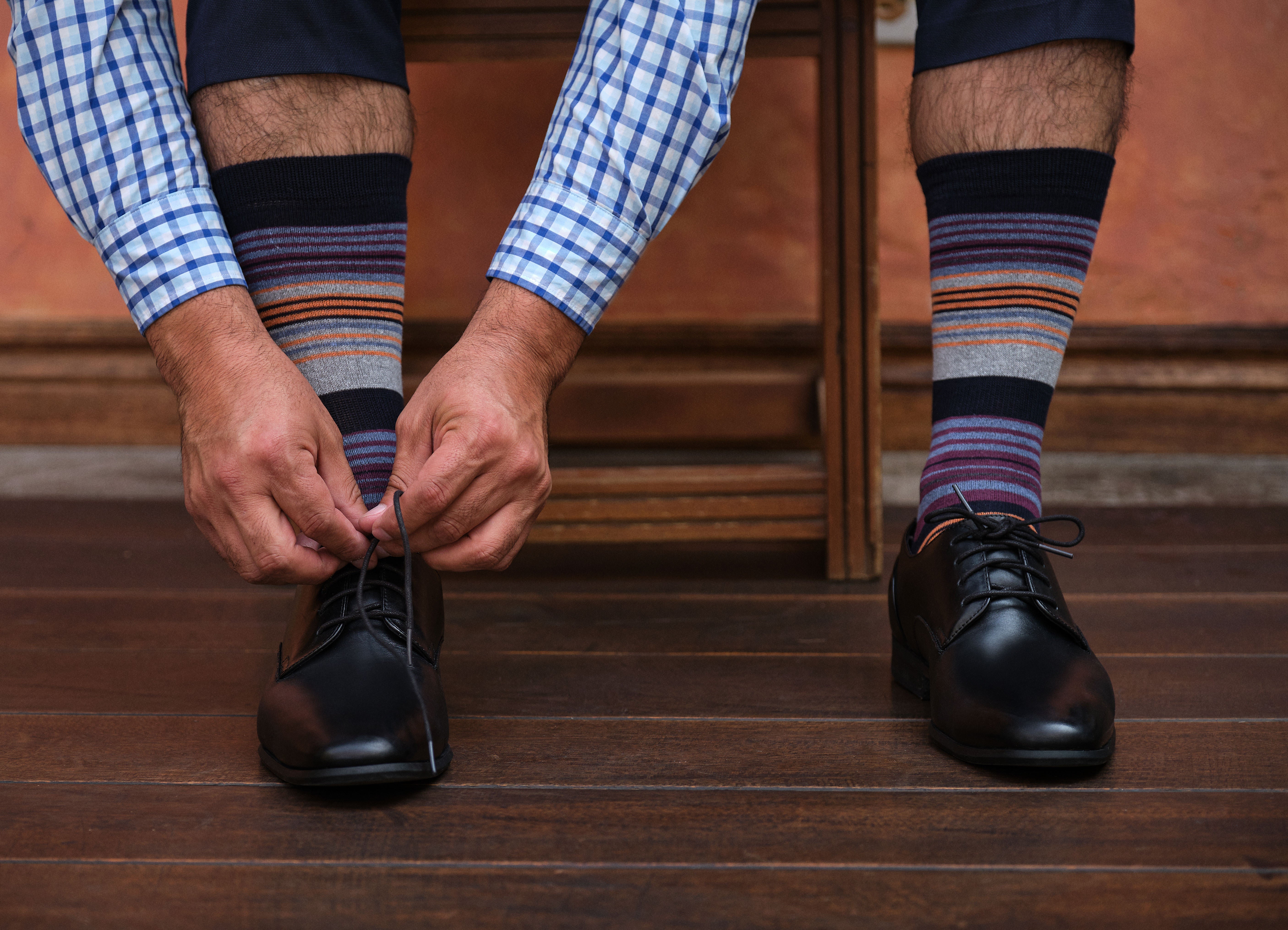 light grey mid calf dress socks with burgundy orange and blue stripes, black dress shoes, plaid dress shirt