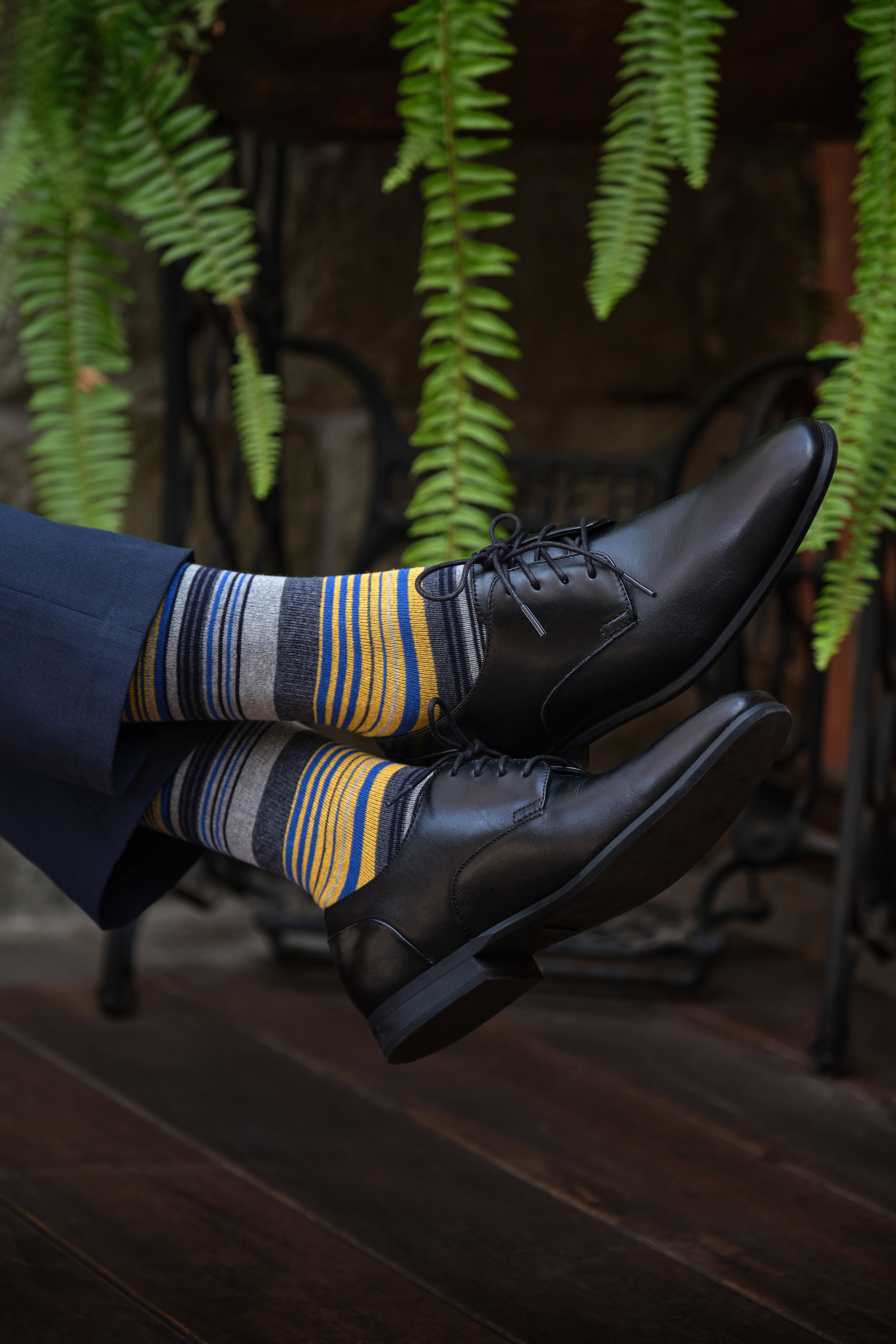 light grey mid calf dress socks with yellow blue and grey stripes, black dress shoes, navy dress pants