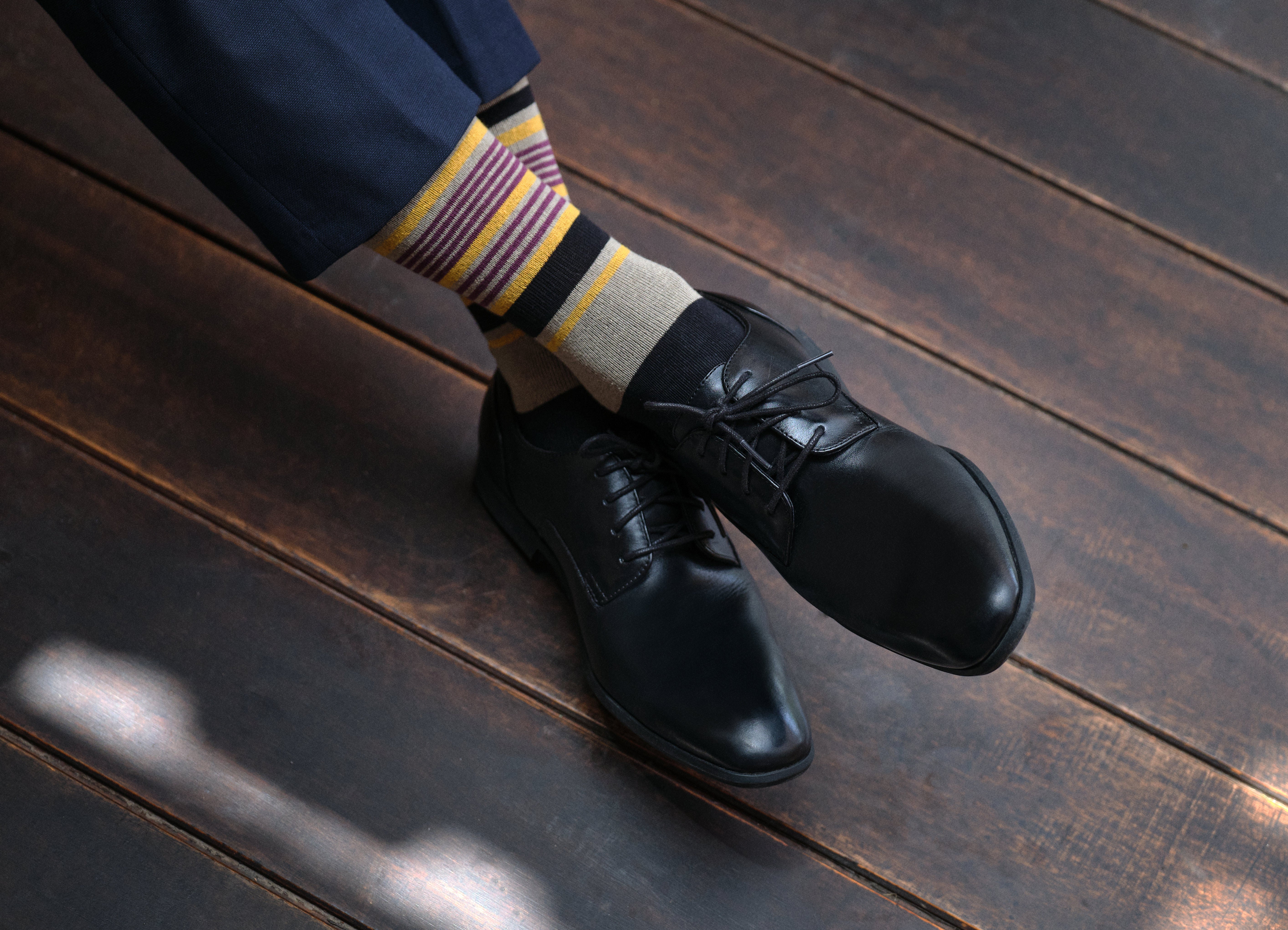 light grey mid calf dress socks with yellow burgundy and black stripes, black dress shoes, navy dress pants