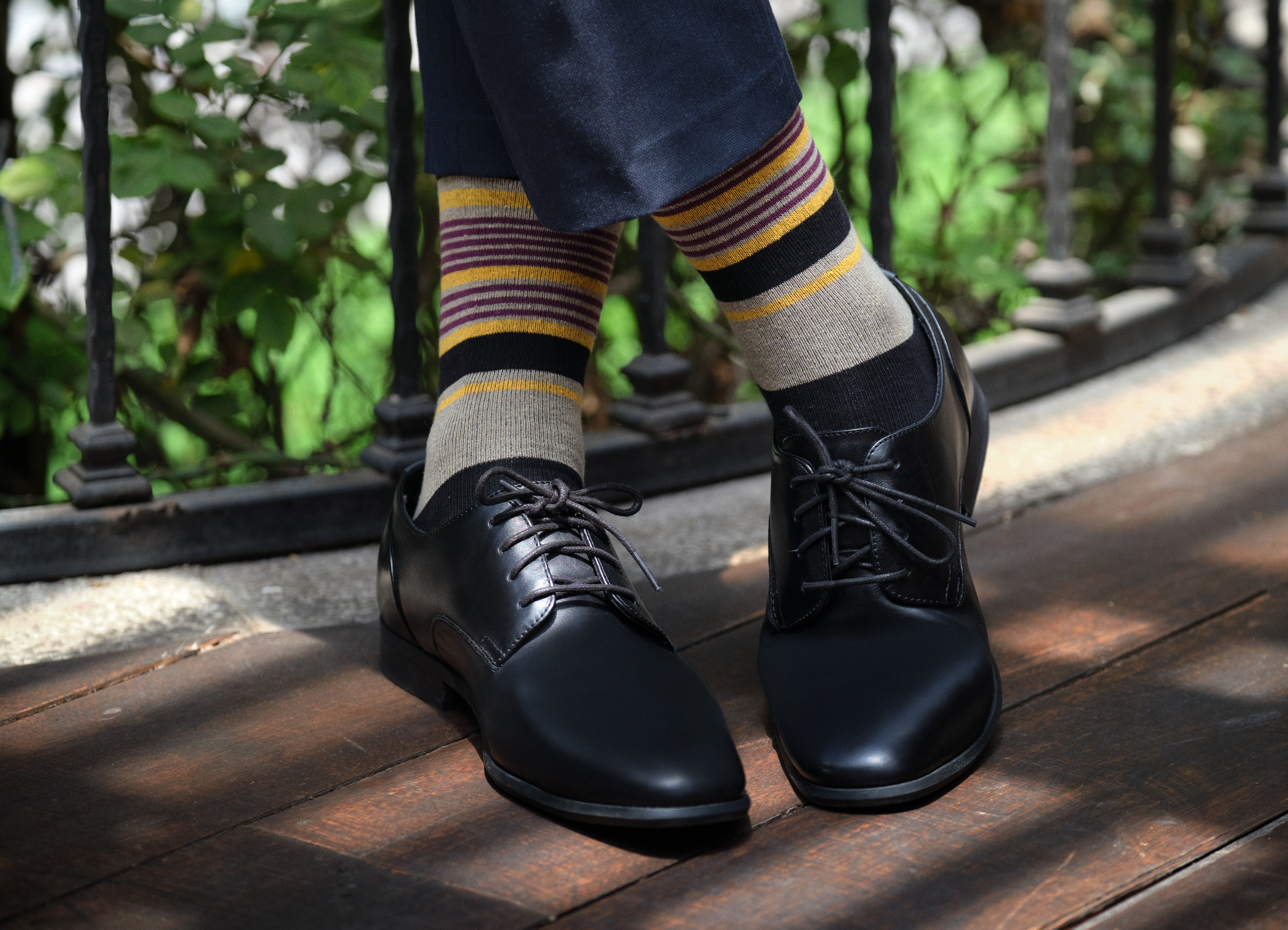 light grey mid calf dress socks with yellow burgundy and black stripes, black dress shoes, navy dress pants