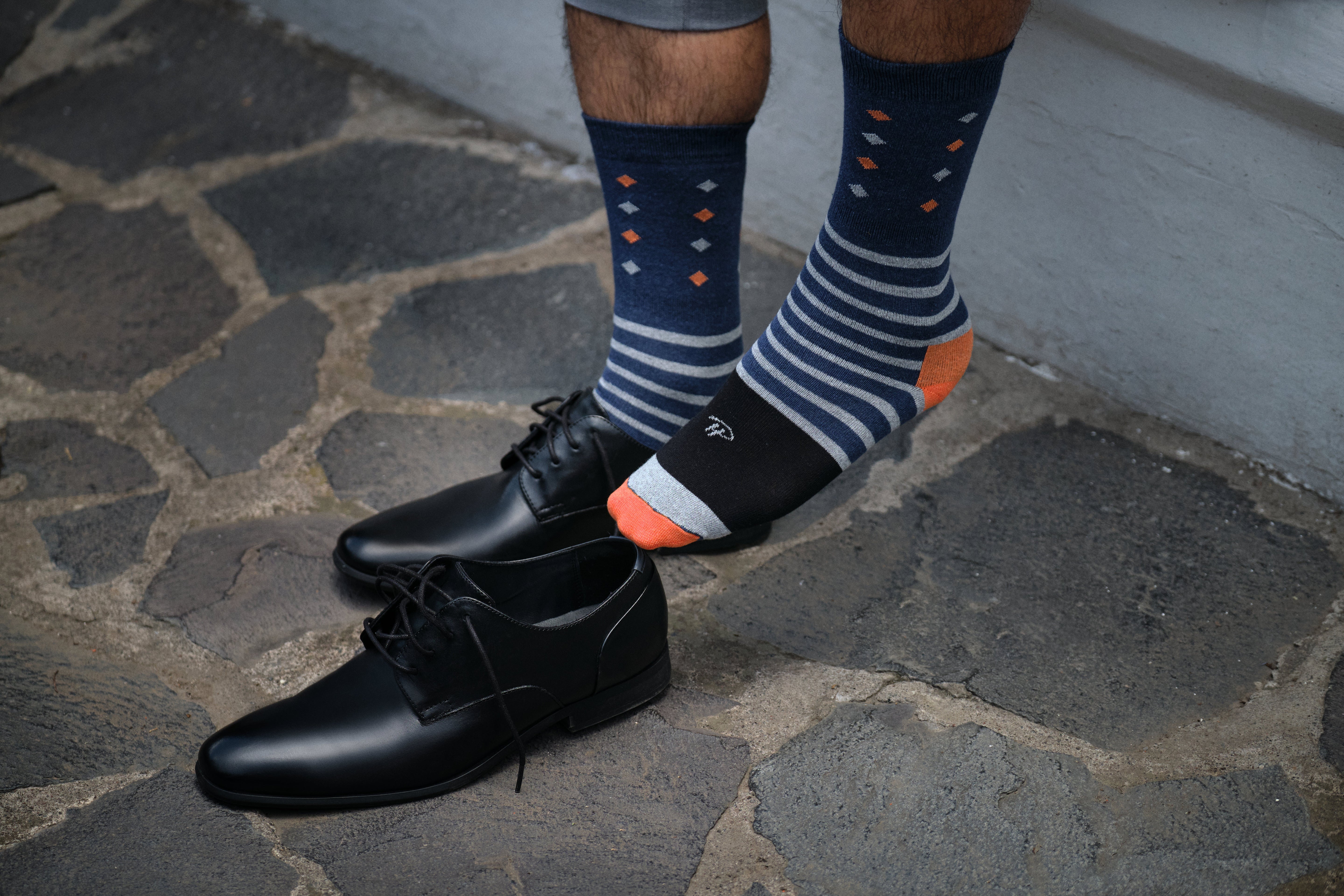 navy blue mid calf dress socks with light blue and orange stripes and prints, black dress shoes