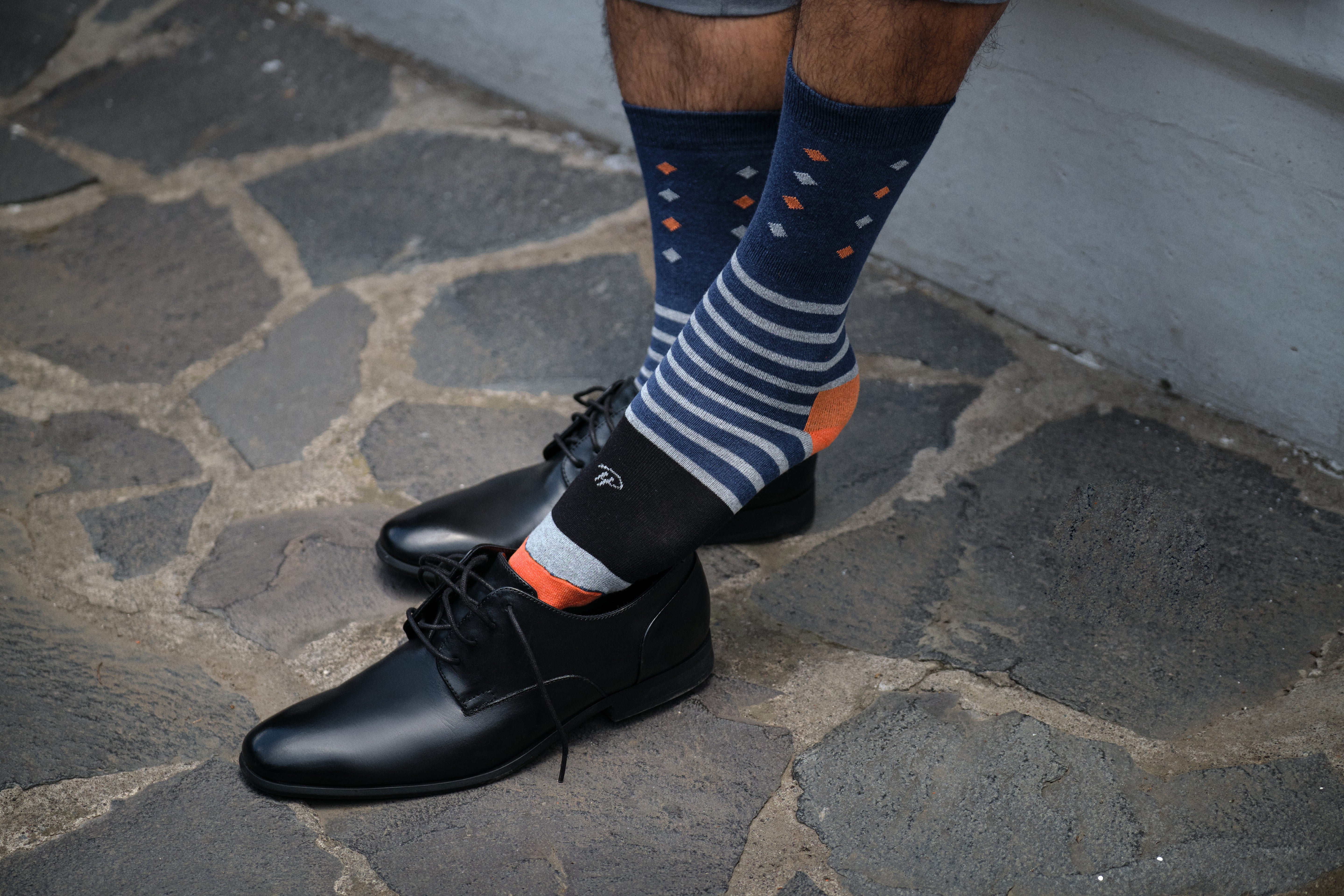 navy blue mid calf dress socks with light blue and orange stripes and prints, black dress shoes
